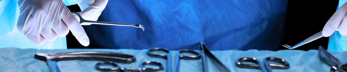 Instrumentarium laparoskopii są wyłożone na stole, przy nim stoi lekarz, który wybiera jedno z nich.